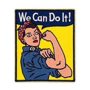 May include: A rectangular embroidered patch featuring a person with a flexed arm, wearing a blue shirt and a red polka-dot headscarf. The background is yellow with a dark blue speech bubble containing the white text We Can Do It!