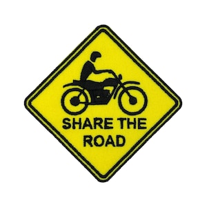 Könnte beinhalten: Gelb-schwarzer, gestickter Aufnäher mit einer Motorrad- und Fahrer-Grafik. Der rautenförmige Aufnäher trägt den Text "SHARE THE ROAD" in schwarzen Blockbuchstaben. Der Rand ist schwarz.