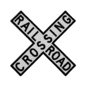 Op de afbeelding: Een wit en zwart geborduurd embleem in de vorm van een X, met de zwarte woorden "RAILROAD CROSSING". De patch heeft een zwarte rand en is bedoeld voor kleding of accessoires.