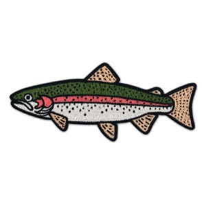 Könnte beinhalten: Ein gestickter Aufnäher in Fischform mit dunkelgrünem Rücken, einem horizontalen rosa Streifen an der Seite und einem weißen Bauch mit kleinen schwarzen Punkten. Die Flossen und der Schwanz sind hellbeige mit schwarzem Rand.