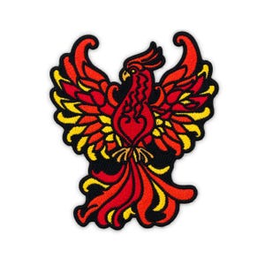 May include: An embroidered patch featuring a stylized phoenix with wings spread wide. The design uses vibrant red, orange, and yellow thread colors against a solid black background, with a thick black border outlining the entire shape.