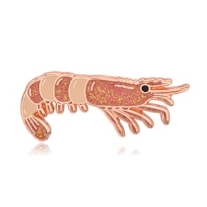 Op de afbeelding: Een roze goudkleurige garnalenpin met een glinsterend roze lichaam en bruine segmenten. De pin heeft een gedetailleerd ontwerp met een zwart oog en delicate poten en antennes. De garnaal is een zeedier en een soort schaaldier.
