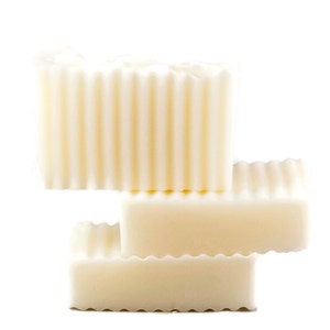 May include: Three bars of white soap stacked on top of each other. The top bar has a ridged texture.