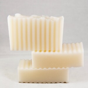 May include: Three bars of white soap stacked on top of each other. The soap has a ridged texture.
