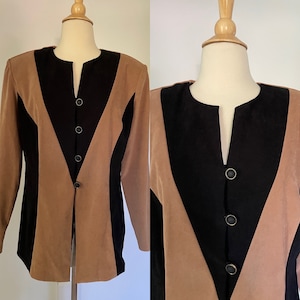 Może przedstawiać: Beżowa, czarna i brązowa marynarka z unikalnym wzorem w bloki kolorów. Marynarka posiada kołnierz z klapami i zapinana jest na trzy czarne guziki. Długi rękaw kurtki jest prezentowany na manekinie.