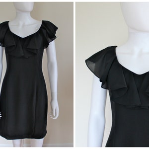 May include: A black dress with a V-neckline and ruffled cap sleeves. The dress is displayed on a mannequin. The dress has a fitted bodice and a knee-length skirt. The fabric appears to be a lightweight material.