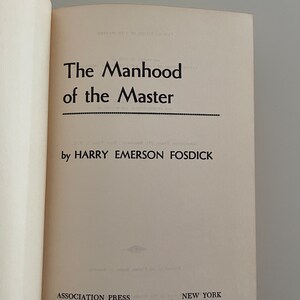 May include: An open book displaying the title "The Manhood of the Master" by Harry Emerson Fosdick. The book has an off-white cover with black text. Published by Association Press, New York.