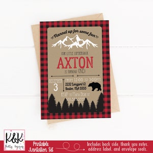 May include: Printable invitation set for a first birthday party with a lumberjack theme. The invitation features a red and black buffalo plaid border, a brown background with a black silhouette of a bear and trees, and the text "Flannel up for some fun." The invitation also includes the child's name, "Axton", and the date and time of the party.