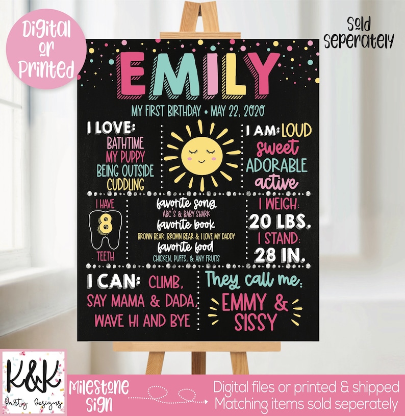 May include: A black chalkboard style sign with a pink, blue, and yellow design. The sign says "Emily" and includes details about her first birthday, including her weight, height, favorite foods, and activities. The sign also includes a sun graphic and a tooth graphic.