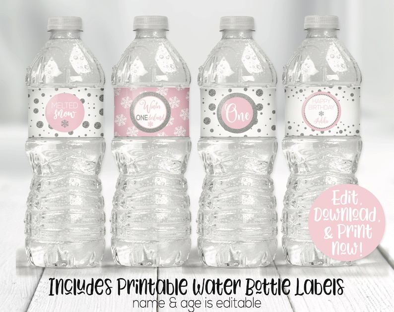 Peut inclure: Quatre bouteilles d'eau en plastique transparent avec des &eacute;tiquettes de flocons de neige et de pois rose et argent. Les &eacute;tiquettes indiquent "Melted Snow", "Winter One", "One" et "Happy Birthday Addie". Le texte "Edit, Download & Print now!" est sur un cercle rose. Le texte "Includes Printable Water Bottle Labels name & age is editable" est sous les bouteilles.