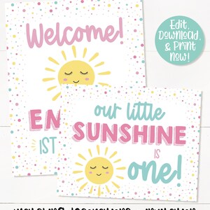 May include: Two printable signs for a first birthday party. The first sign says "Welcome!" with a yellow sun with a smiling face. The second sign says "Our little sunshine is one!" with a yellow sun with a smiling face. Both signs have a white background with pink, yellow, and blue confetti.