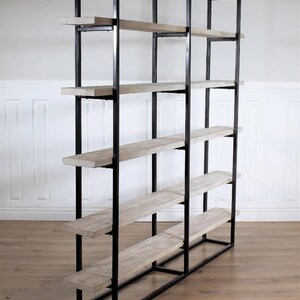 May include: A black metal bookshelf with six wooden shelves. The shelves are made of light-colored wood and are evenly spaced.