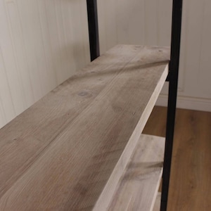 May include: A wooden shelf unit with black metal supports. The shelves are made of natural wood with a light brown finish.