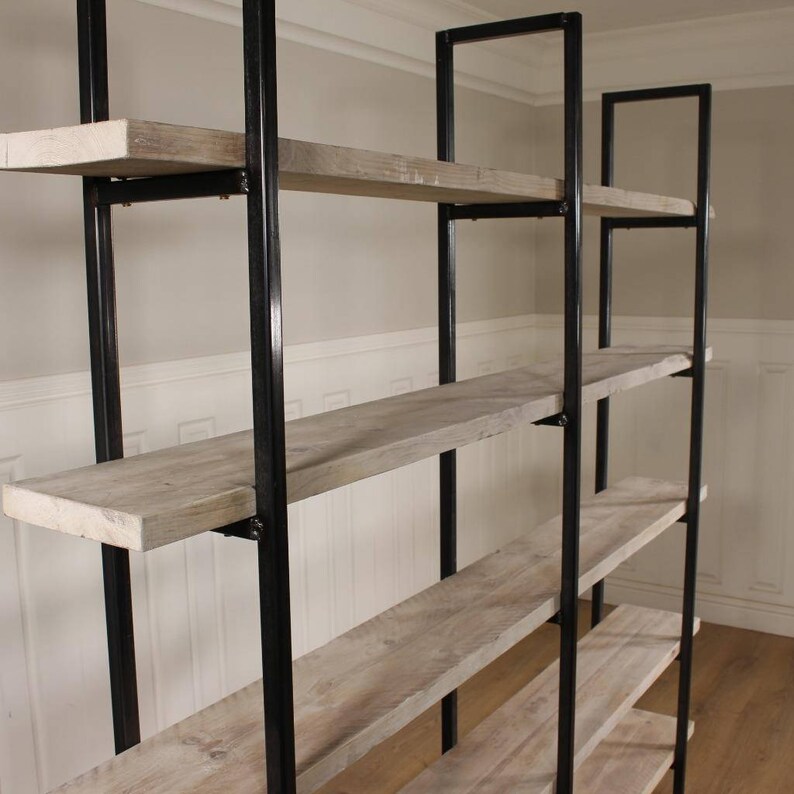 May include: A tall, industrial-style bookshelf with five shelves made of reclaimed wood. The shelves are supported by black metal frames.
