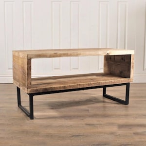 May include: A rustic wooden coffee table with a single open shelf and black metal legs. The table has a natural wood finish and a rectangular shape.