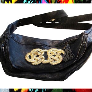 Pode incluir: Uma pochete de couro preto com um design dourado em n&oacute; na frente. A bolsa tem um fecho de correr e uma al&ccedil;a longa ajust&aacute;vel.