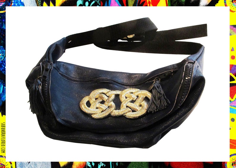 Pode incluir: Uma pochete de couro preto com um design dourado em n&oacute; na frente. A bolsa tem um fecho de correr e uma al&ccedil;a longa ajust&aacute;vel.
