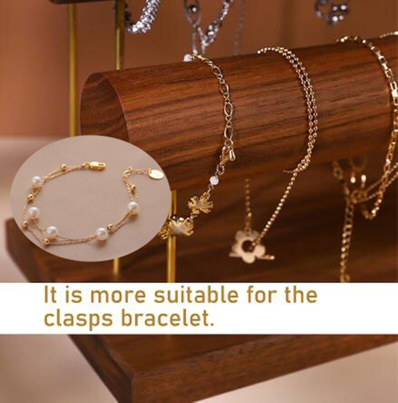 May include: A gold bracelet with pearls and small gold beads is displayed on a wooden jewellery stand. The stand has a dark brown finish and is holding several gold necklaces and bracelets. The text in the image reads: "It is more suitable for the clasps bracelet."