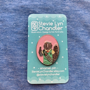 May include: A light pink and green enamel pin featuring a cartoon squirrel wearing a green Girl Scout uniform and holding a cookie box. The pin is on a white card with blue polka dots and the text "SC Stevie Lyn Chandler Illustration, Design & Pet Portraits enamel pin - StevieLynChandler.etsy.com @stevielynchandler".