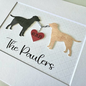 May include: A framed print with two black and tan dog silhouettes connected by a red heart with the date 10.21.23 and the text "The Paulers" below.