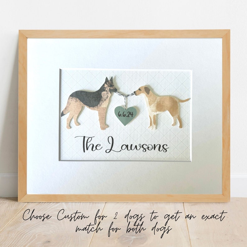 May include: A framed print with two dogs, a German Shepherd and a Labrador Retriever, holding a heart with the date "6.6.24" and the text "The Lawsons".