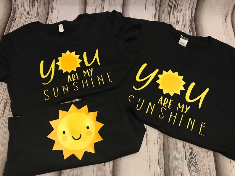 May include: Two black t-shirts with the text "You are my sunshine" and a yellow sun graphic.