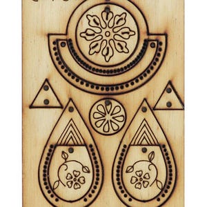 Könnte beinhalten: Holzschablone zum Herstellen von Ohrringen. Die Schablone enthält zwei Tropfenformen mit Blumenmustern, einen Kreis mit einem Blumenmuster, eine Halbmondform mit einem Perlenrand und zwei Dreiecke.