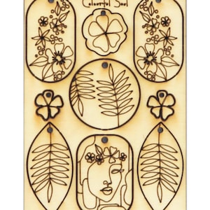 Könnte beinhalten: Eine Platte aus unbehandeltem Holz mit neun lasergeschnittenen Designs. Die Designs beinhalten Blumen, Blätter und ein stilisiertes Gesicht mit einer Blumenkrone. Der Text "Colourful Soul" ist oben auf der Platte gedruckt.