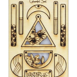 Könnte beinhalten: Holzbastelset mit lasergeschnittenen Teilen zum Erstellen eines Mobiles mit einer Sichelmond, einem Dreieck und zwei Halbkreisen. Das Set enthält den Text "Colorful Soul" und "Wanderlust".