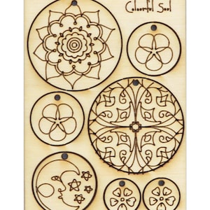 Könnte beinhalten: Eine Holzplatte mit sieben runden Ausschnitten, die jeweils ein anderes Design zeigen. Die Designs umfassen ein Mandala, eine Blume, einen Halbmond und Sterne. Der Text "Colorful Soul" ist in der oberen rechten Ecke gedruckt.