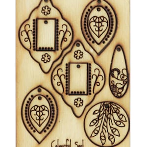 Könnte beinhalten: Eine Holzplatte mit sechs lasergeschnittenen Formen, darunter ein Herz, ein Kreis und ein Rechteck. Die Formen sind mit filigranen Designs verziert und die Worte "Colourful Soul" sind unten aufgedruckt.