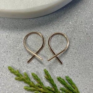 May include: A pair of gold-toned hoop earrings with a unique, twisted design. The earrings are small and delicate, making them a perfect choice for everyday wear.