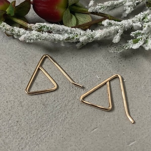 May include: A pair of gold triangle shaped earrings with a curved wire.