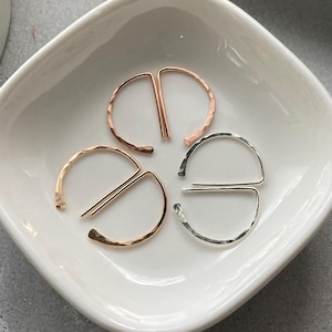May include: Three pairs of hammered metal earrings in gold, rose gold, and silver. Each earring is a half circle with a straight bar across the top.