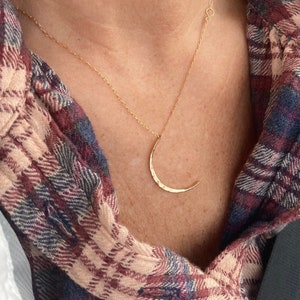 May include: A gold necklace with a hammered crescent moon pendant.