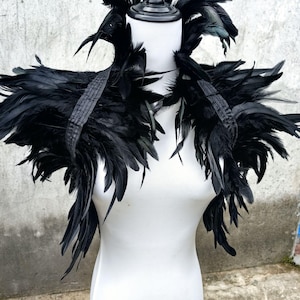 May include: Black feather shoulder piece with a large collar. The feathers are arranged in a layered, cascading design.
