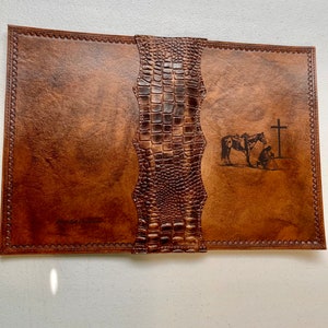 May include: A brown leather journal with a crocodile embossed cover. The journal has a cross and a horse with a rider engraved on the front cover. The text "Blessed Treasures" is embossed on the front cover.