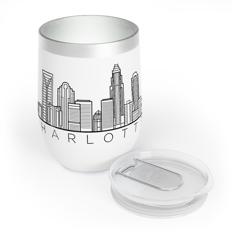 May include: White stainless steel travel mug with a black outline of the Charlotte skyline and the word "CHARLOTTE" printed below. The mug has a clear lid with a silver slider.