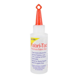 May include: A clear plastic bottle of Fabri-Tac Premium Fabric Glue with a red cap and a red applicator tip. The bottle is labeled with the product name and instructions for use. The bottle contains 2 fl oz (59 ml) of glue.