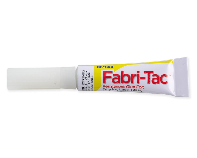 May include: A yellow tube of Fabri-Tac permanent glue for fabrics, lace, and glass. The tube is labeled "BEACON Fabri-Tac Permanent Glue For. Fabrics, Lace, Glass."