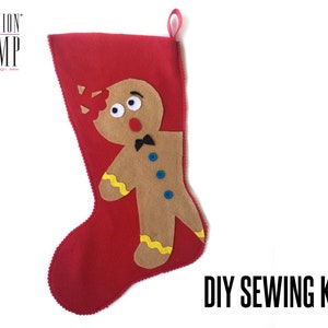 Könnte beinhalten: DIY Nähset zum Herstellen eines roten Filz-Weihnachtsstrumpfes mit einer Lebkuchenmann-Applikation. Der Lebkuchenmann hat einen braunen Filzkörper, gelben Zuckerguss und blaue Knöpfe.