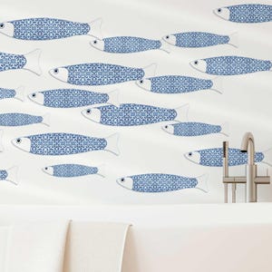Puede incluir: Un vinilo decorativo de pared con un grupo de peces azules y blancos estampados nadando por una pared blanca. Los peces tienen un diseño decorativo. La escena incluye una bañera blanca y un taburete de madera. Los peces están dispuestos en un patrón fluido.