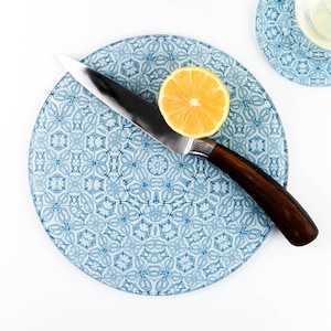 May include: A blue and white patterned glass chopping board with a silver knife and a lemon wedge on top.