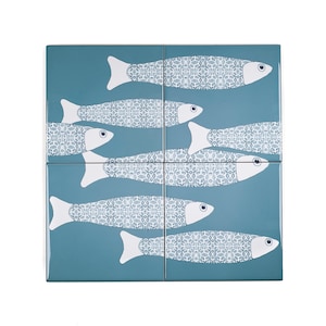 May include: A set of four blue ceramic tiles with a white fish design. Each tile features a stylized fish with a patterned body and a white outline.