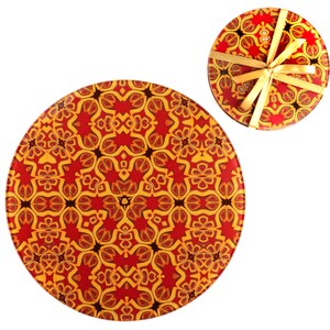 May include: Two round coasters featuring a red, yellow and black geometric design. The smaller coaster has a gold ribbon tied around it.