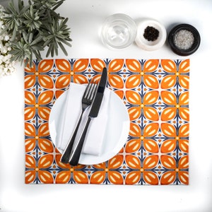 May include: A white ceramic plate with a fork and knife on a placemat with a repeating orange, blue and white geometric pattern.