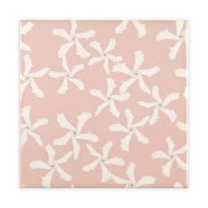 Op de afbeelding: Een roze keramische tegel met een herhalend patroon van witte gestileerde bloemen. De bloemen zijn symmetrisch gerangschikt en hebben een licht abstract ontwerp.