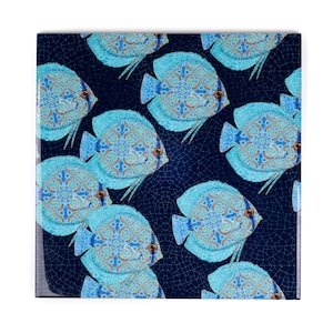 May include: A blue and white ceramic tile with a repeating pattern of blue fish with intricate designs. The fish are set against a dark blue background with a cracked glaze effect.
