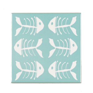 May include: Square ceramic tile featuring a light blue background and a repeating pattern of white fish skeleton designs. Suitable for kitchens or bathrooms, this tile is a decorative element.