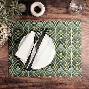 May include: A green and blue patterned placemat with a white plate, a white napkin, a silver fork, and a silver knife.